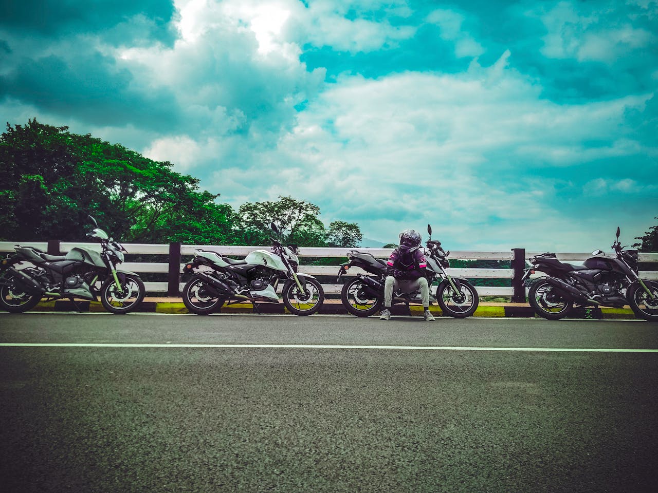 about-us A motorcyclist takes a break on a scenic road in Palakkad, Kerala, surrounded by motorcycles.