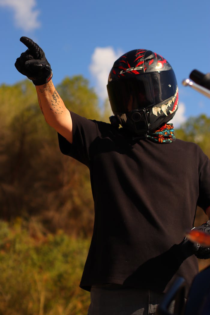 our-story A motorcyclist with a unique helmet gestures outdoors, showcasing adventure and freedom.